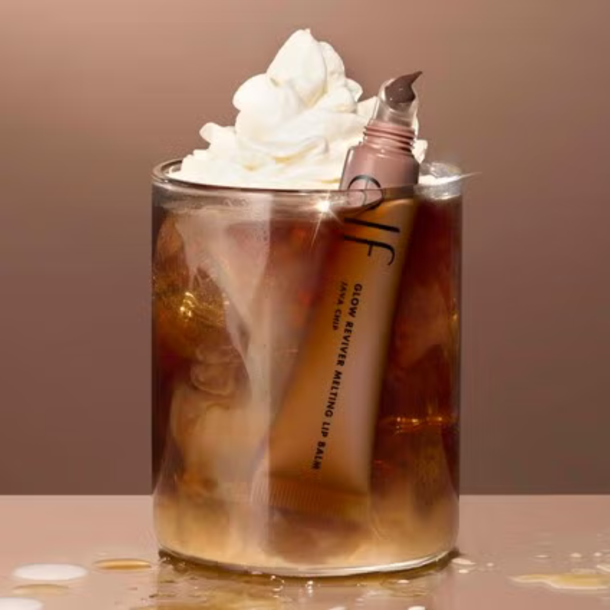 Roll-on bottle of skincare product in a glass of iced coffee with whipped cream.
