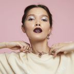 Woman wearing a silver liquid glitter eyeshadow and a necklace with a lock pendant against a pink background