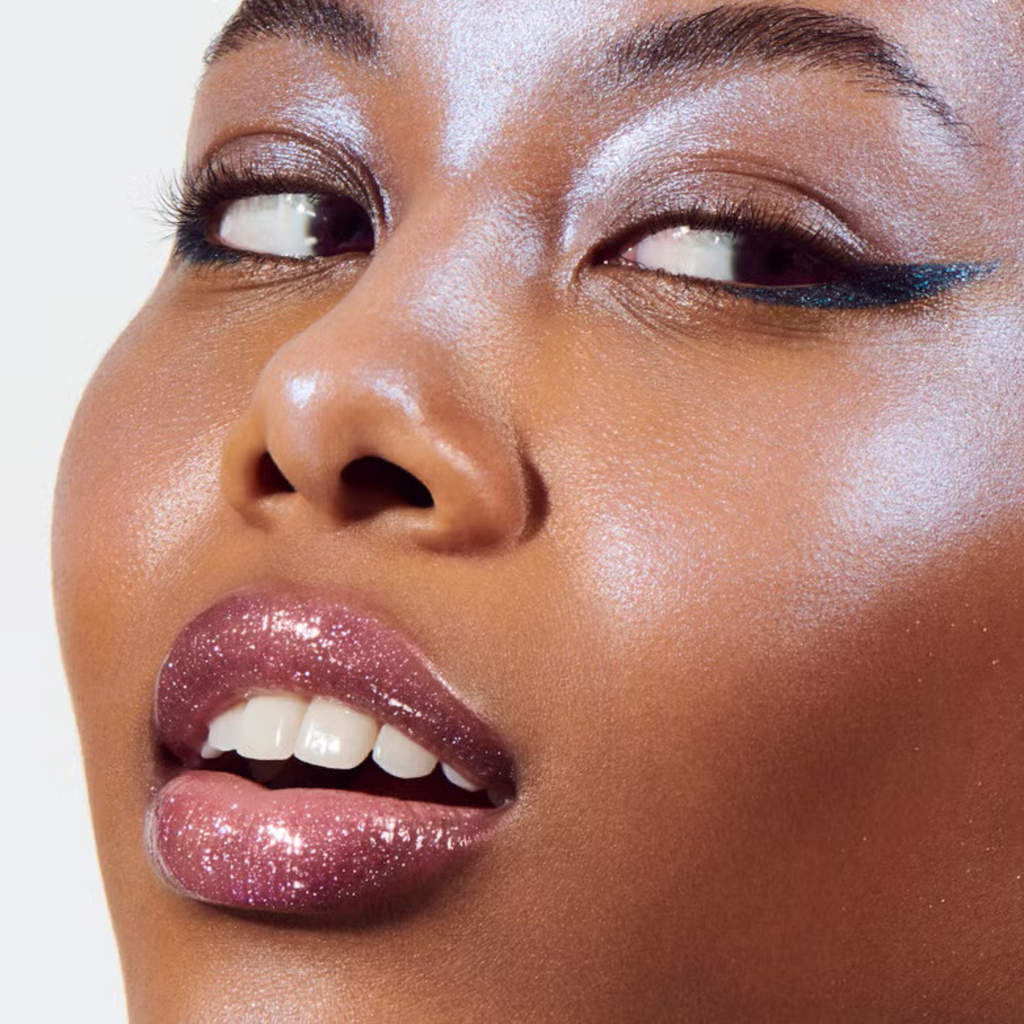 Model draagt e.l.f. Prismatic Lip Gloss Amethyst voor glanzende, volumineus ogende lippen.