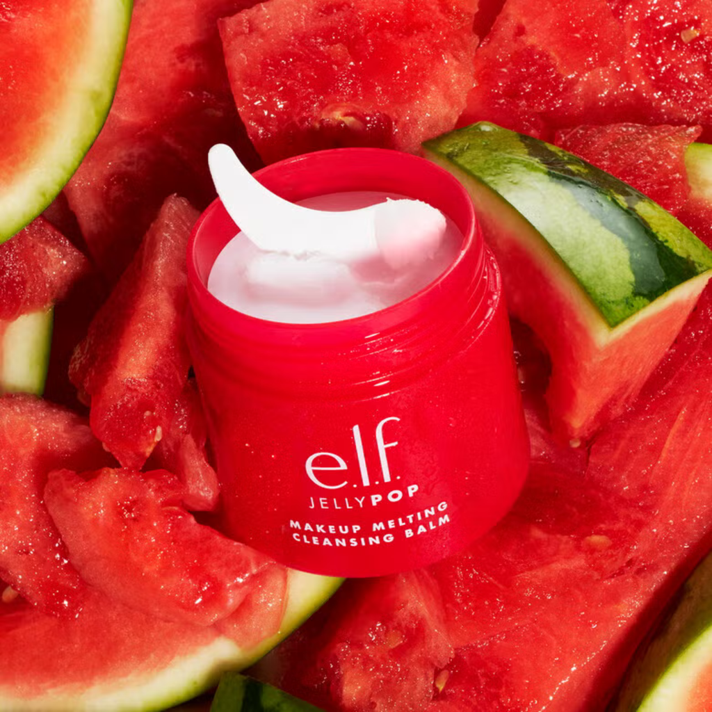 Red makeup cleansing balm jar with a white applicator on watermelon slices.