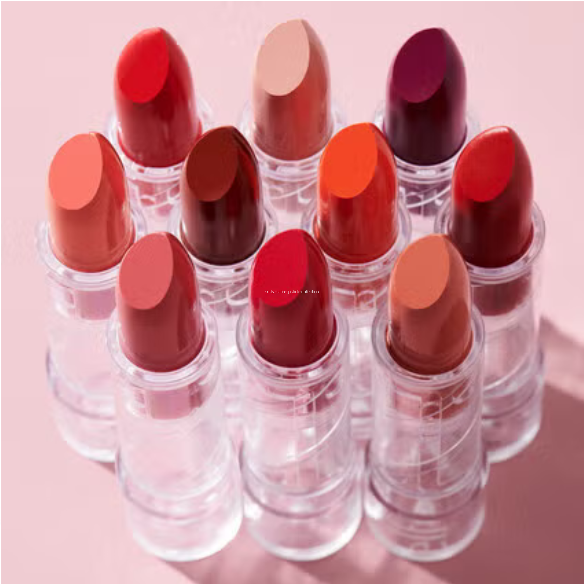 Set of red lipsticks with clear casings on a pink background